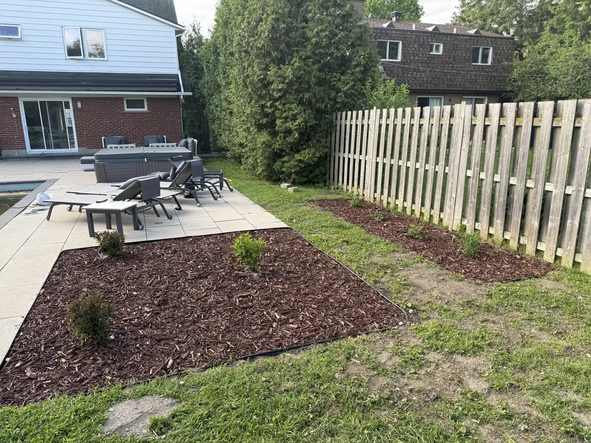Backyard garden bed with mulch and edging beside a patio