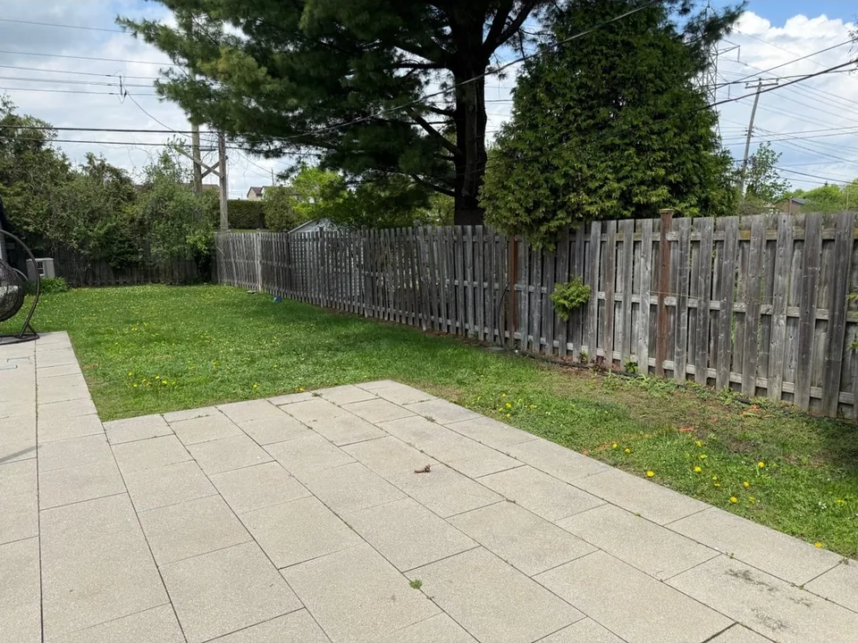 Pelouse à côté d’un patio et d’une clôture en bois — avant