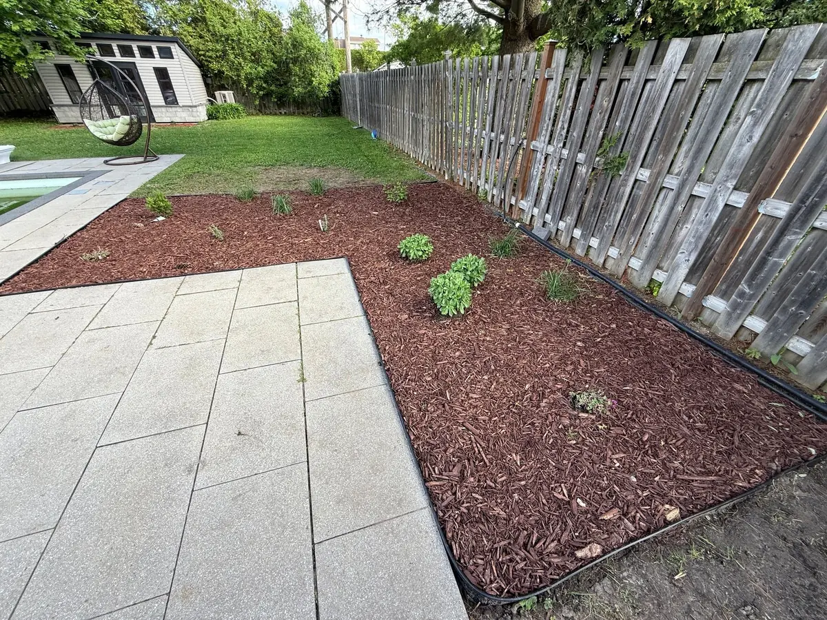 Garden bed with fresh mulch beside a large-format stone patio